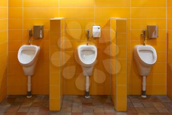 Three urinal in the bathroom with yellow walls