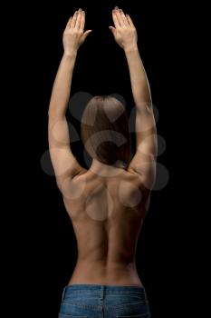 Studio photo, young, slim, athletic girl with a naked back in blue jeans held up his hands. Isolate on black.