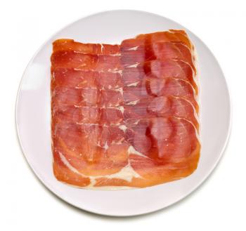 Apetitnye slices of jamon on a round plate. Isolate on white.