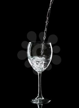 Wine glass with water over black background