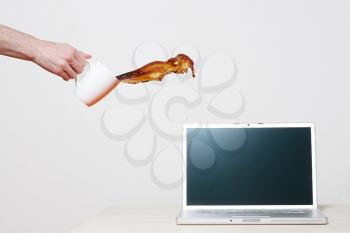 Royalty Free Photo of a Person Pouring Coffee on a Laptop