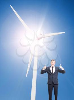 A wind turbine on a asunny day and a man