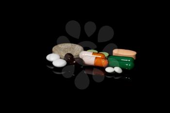 assorted medicine pills on black background with reflections
