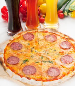 Italian original thin crust pepperoni pizza with selection of beers and vegetables on background