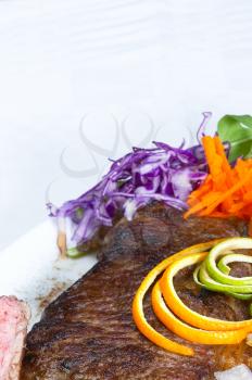 fresh juicy beef ribeye steak grilled with orange and lemon peel on top and vegetables beside