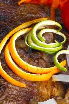 fresh juicy beef ribeye steak grilled with orange and lemon peel on top and vegetables beside