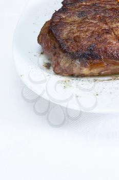 fresh juicy beef ribeye steak grilled on a plate over a table