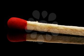 single matchstick with reflection over black background