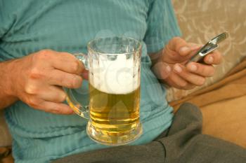 Royalty Free Photo of a Man Holding a Cellphone and Beer