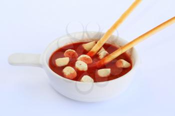 Croutons and bread sticks in red sauce on gray background.