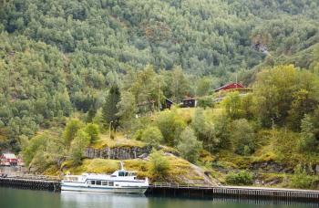 Landscape with Naeroyfjord, ship, mountains and traditional houses in Norway.