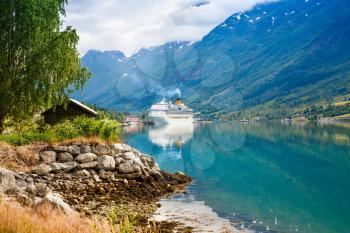 Landscape with mountains, cruise liner, village and fjord in Norway.