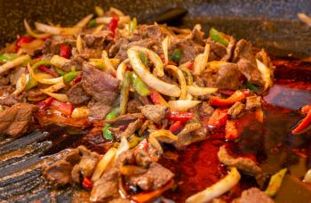 Mexican food. Beef fajitas with onion and colorful bell peppers in frying pan.