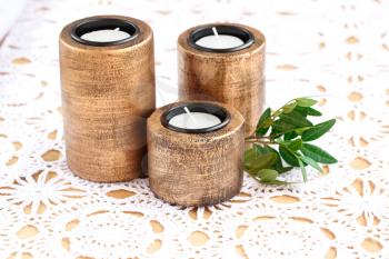 Three brown ancient style candle nests and green leaves on cloth background.