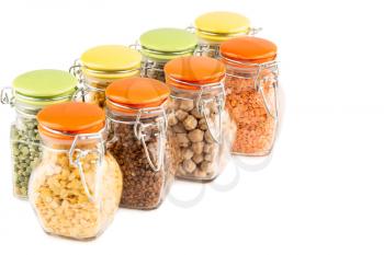The collection of different groats in the glass jars isolated on white background. Buckwheat, chickpea, pea and lentils.