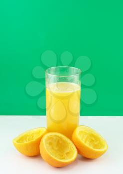 Glass of fresh orange juice with squeeze slice on green background..