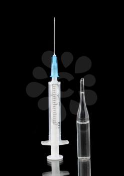 Syringe and ampule with medication on black background.