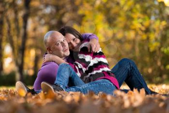 Happy Couple Sitting Together In The Woods During Autumn