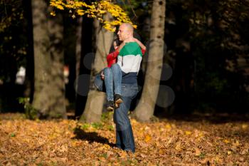 Man Carrying Woman Ride Through Autumn Woods