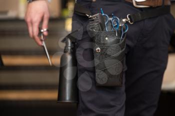 Tools Of A Professional Hairdresser Neatly Stored In A Leather Belt And Pouch Worn Around His Waist In The Hair Salon