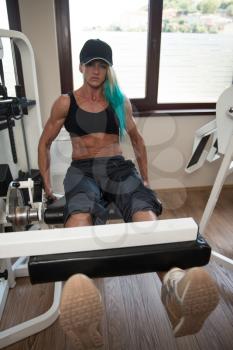 Middle Aged Woman Doing Leg Exercises With Machine In Gym