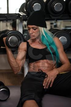 Middle Aged Woman Doing Heavy Weight Exercise For Biceps With Dumbbells In Fitness Centar