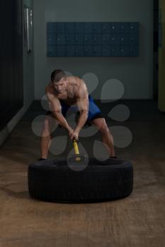 Athletic Man Hits Tire - Workout At Gym With Hammer And Tractor Tire