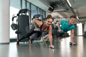 Young Couple Doing Exercise With Dumbbells In The Gym