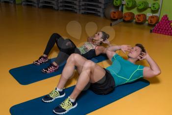 Strong Young Women And Man Exercising Abs Abdominals In Fitness Club