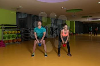 Young Women And Man Doing Exercise With Kettle Bell In The Gym