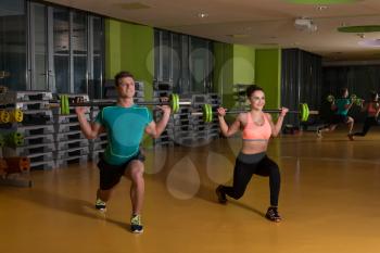 Young Couple Working Out Legs With Barbell In Fitness Center - Squat