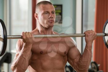Muscular Man Doing Heavy Weight Exercise For Biceps With Barbell
