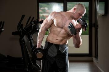 Bodybuilder Doing Heavy Weight Exercise For Biceps With Dumbbells In Gym