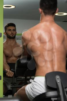 Young Healthy Arabic Man Working Out Biceps - Machine Concentration Curls