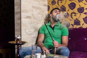 Man Smoking Turkish Hookah In The Cafe With Colorful Walls On Background