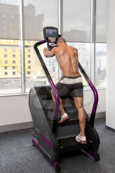 Handsome Man Exercising On A Stepper In Gym Back View