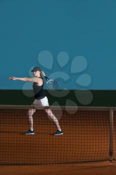 Female Tennis Player Reaching To Hit The Tennis Ball On Court