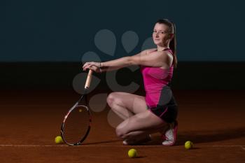 Portrait Of Female Tennis Player With Racket Ready To Hit A Tennis Ball