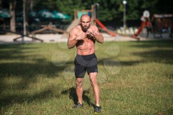 Adult Muscular Sports Guy With A Naked Torso Is Boxing - Doing Street Workout Exercises In Park