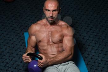 Muscular Man Exercising Abs Abdominals With Kettlebell On Floor