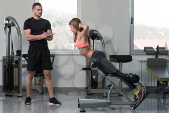 Personal Trainer Working With A Young Woman At The Gym Writing Notes On A Clipboard In A Health And Fitness Concept