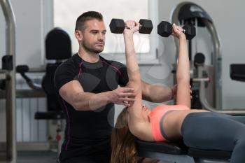 Personal Trainer Showing Young Woman How To Train Chest Exercise With Dumbbells In A Gym