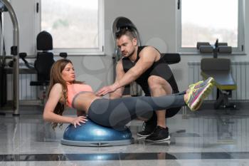 Personal Trainer Showing Young Woman How To Train On Bosu Abs Exercise In A Health And Fitness Concept
