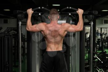 Young Man Athlete Doing Pull Ups - Chin-Ups In The Gym