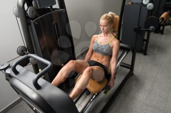 Healthy Young Woman Using The Leg Press Machine At A Health Club In Gym