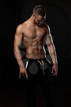 Handsome Geek Man Standing Strong In The Gym And Flexing Muscles - Muscular Athletic Bodybuilder Fitness Model Posing After Exercises
