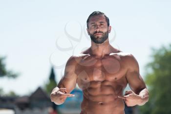 Portrait Of A Physically Fit Man Showing Abs Outdoors
