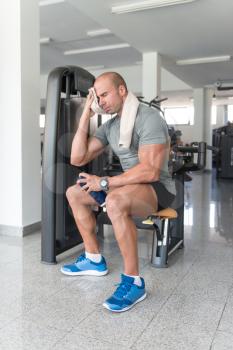 Muscular Man Resting After Exercise And Wipes The Sweat With Towel