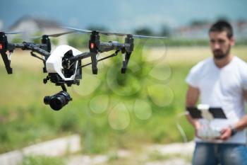 Man Operating Drone Flying or Hovering by Remote Control in Nature