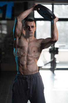 Muscular Man Exercising Abdominal Muscles With Weights In A Modern Fitness Club